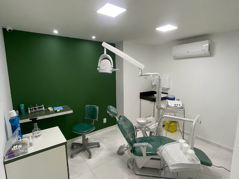 Consultório odontológico com parede verde, cadeira e equipamentos